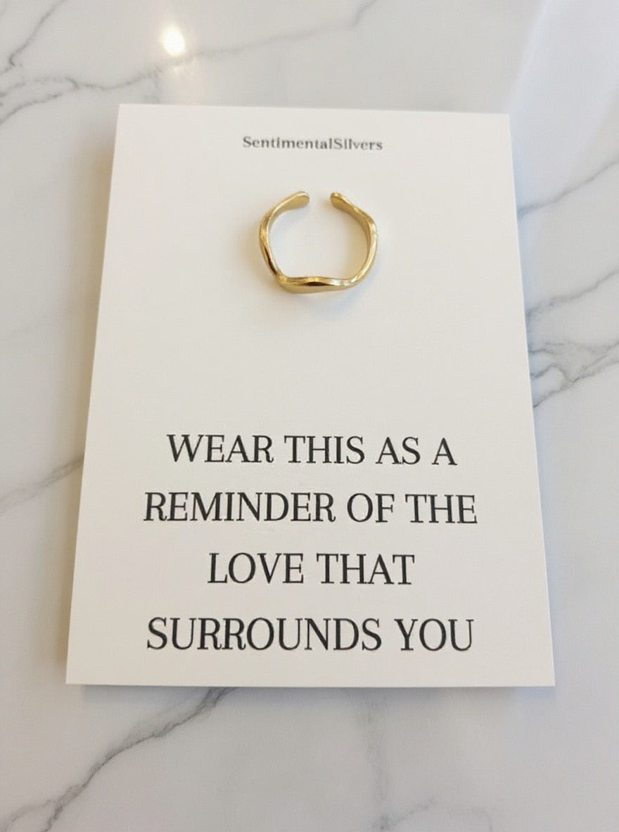 Gold ring on a white card with text on a marble background